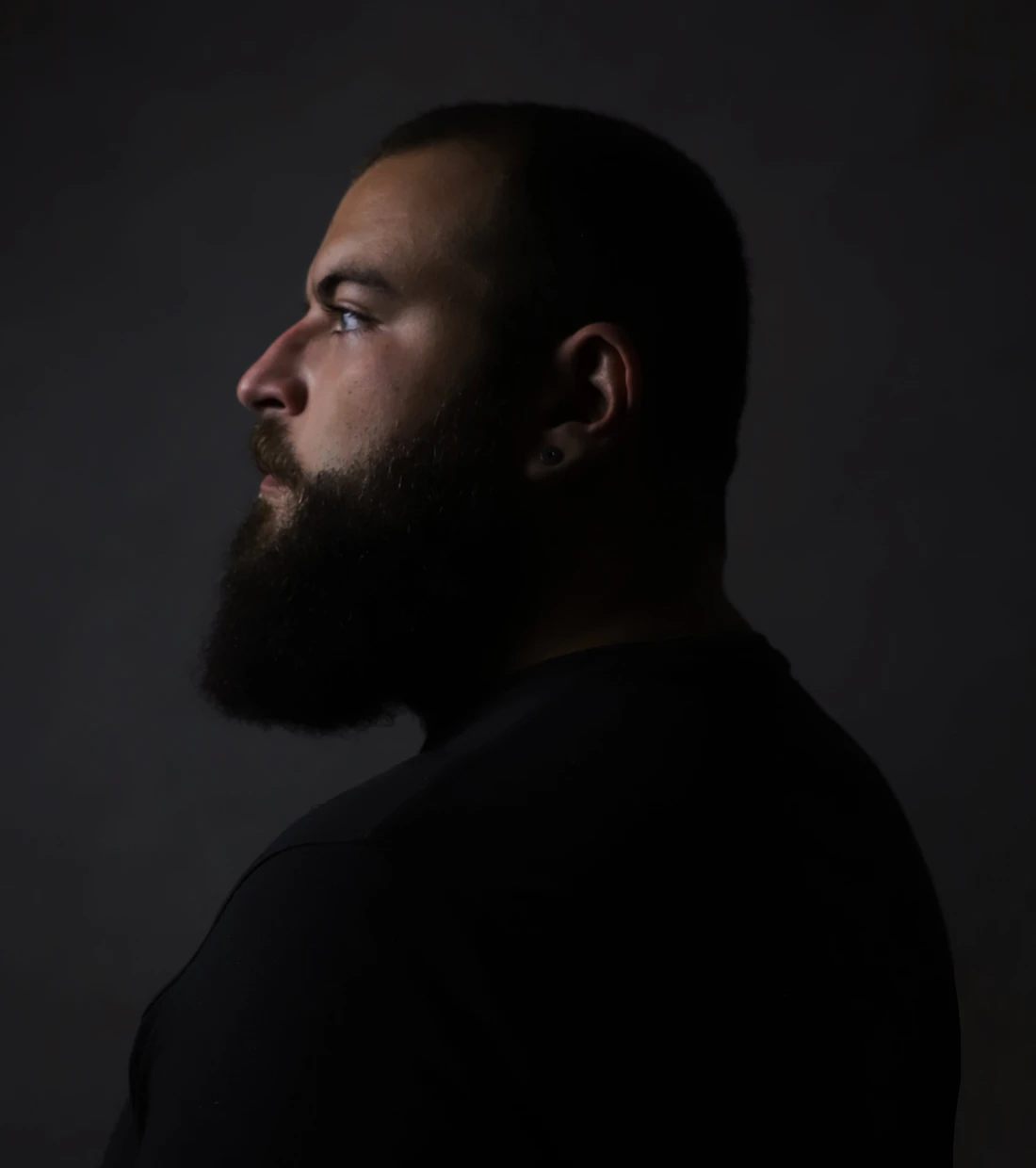 Bearded man in profile against a dark background