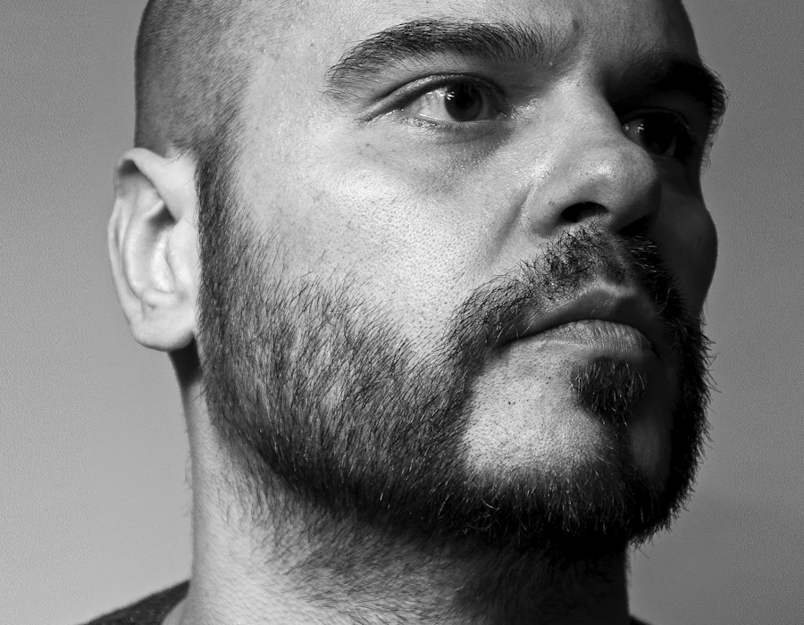 Man with a shaved head and beard, shown in profile