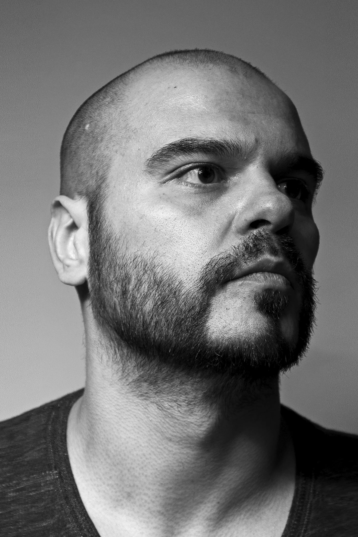 Man with a shaved head and beard, shown in profile