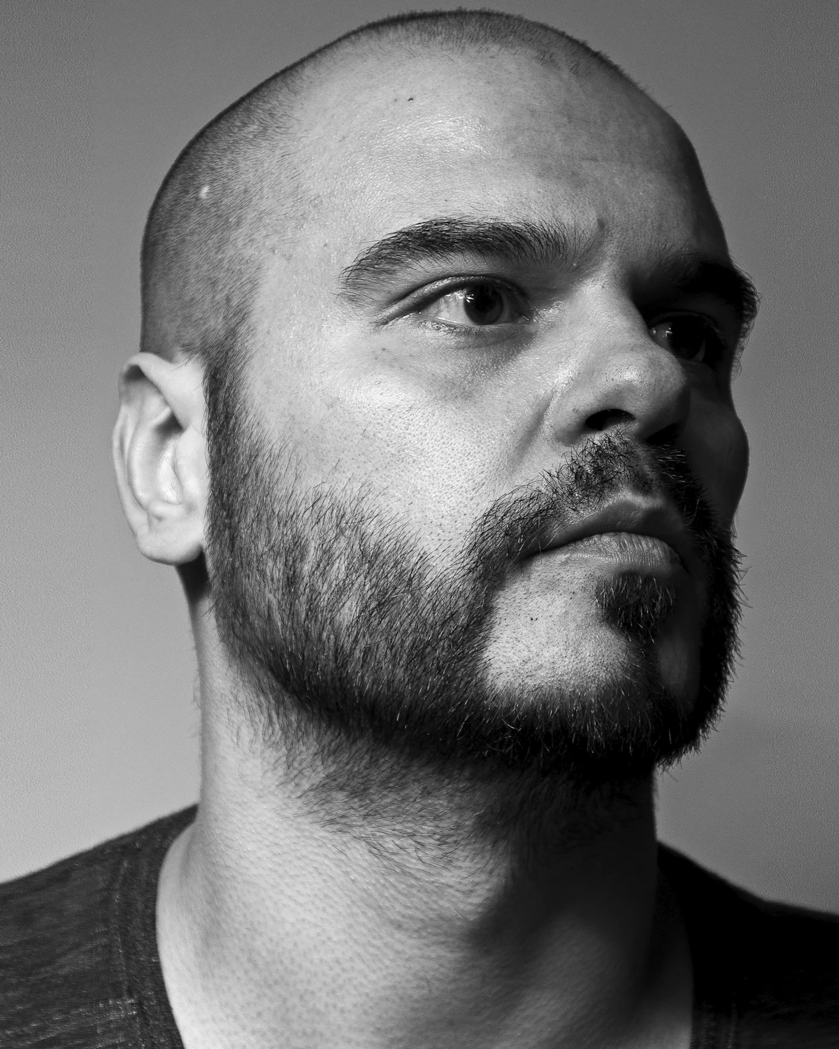 Man with a shaved head and beard, shown in profile
